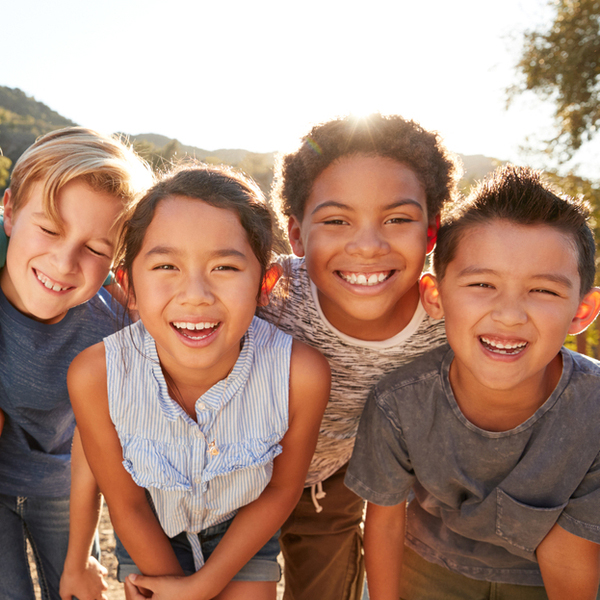 4 Children Laughing and Smiling Next To Each Other